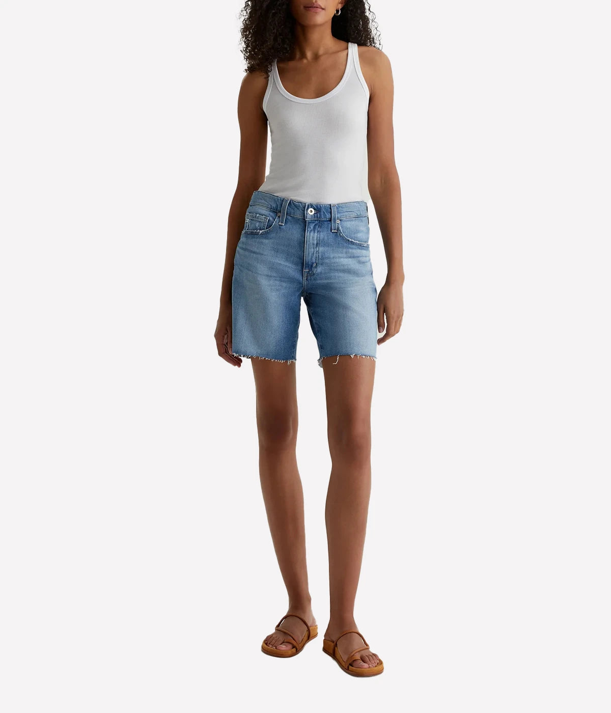 ALT text: Model wears AG mid-rise Ex-Boyfriend Bermuda shorts in faded blue denim with raw hems and light distressing