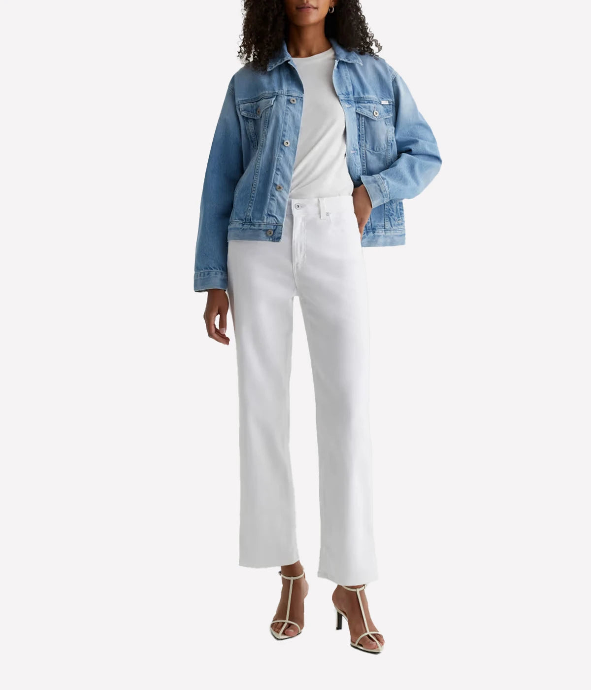 Person wearing a denim jacket and white pants on a white background