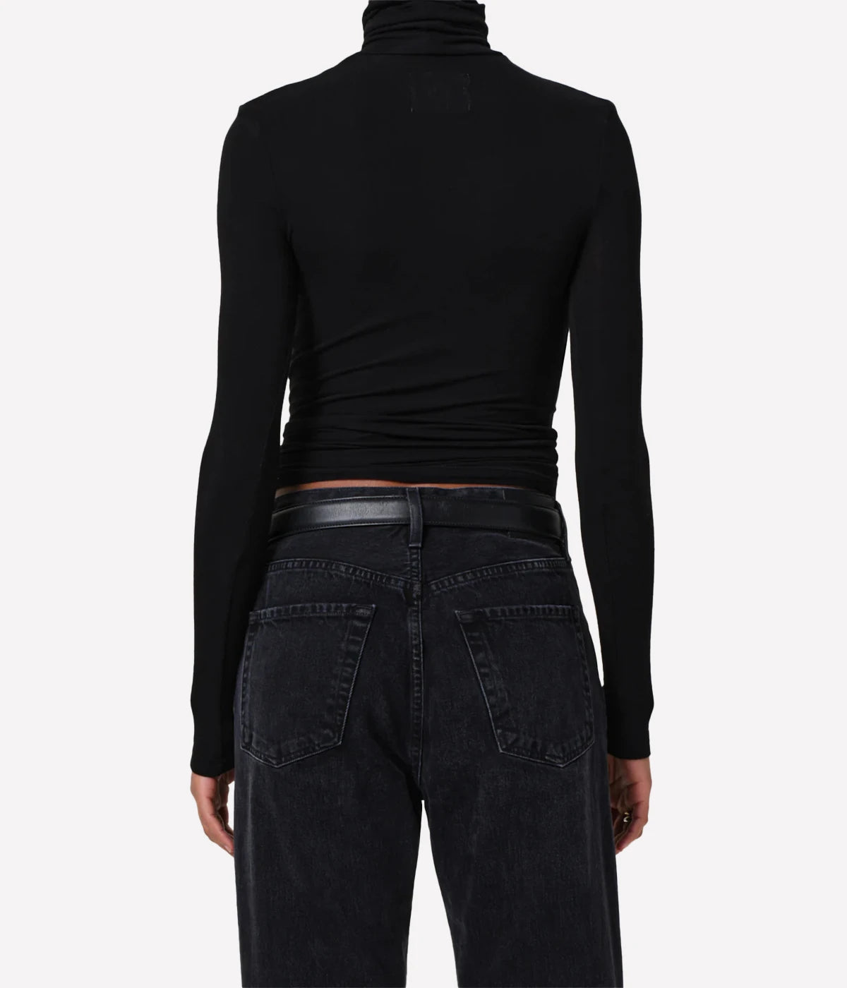 Person wearing a black turtleneck and black jeans from behind on a white background