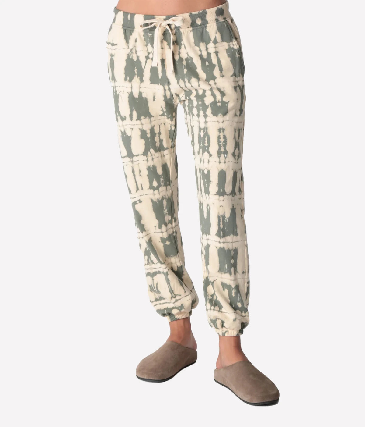 Front view of a model wearing the Electric Rose Classic Horizon Jogger in Moss Ivory, showing the moss and ivory tie-dye, drawstring waist and elasticated cuffs, with taupe suede clogs