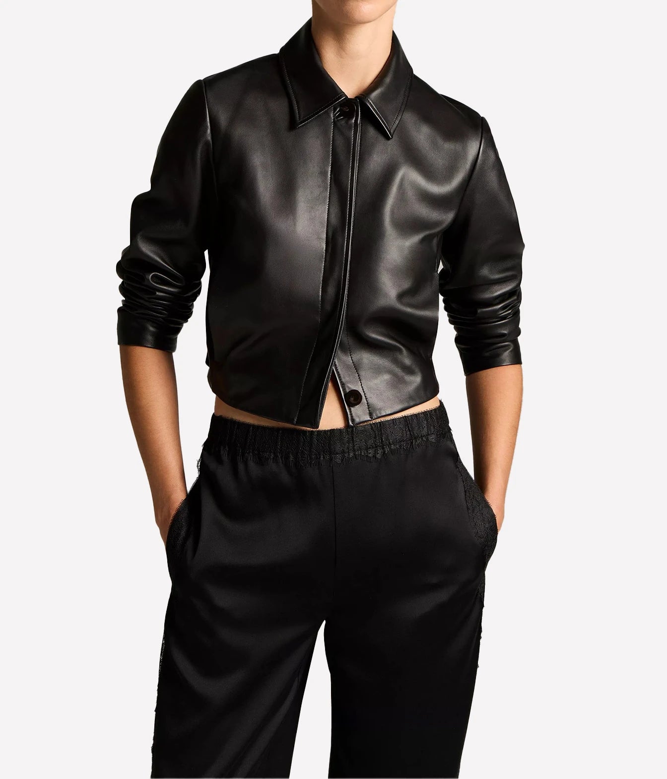 A model wearing a black leather cropped jacket with a pointed collar and front zipper