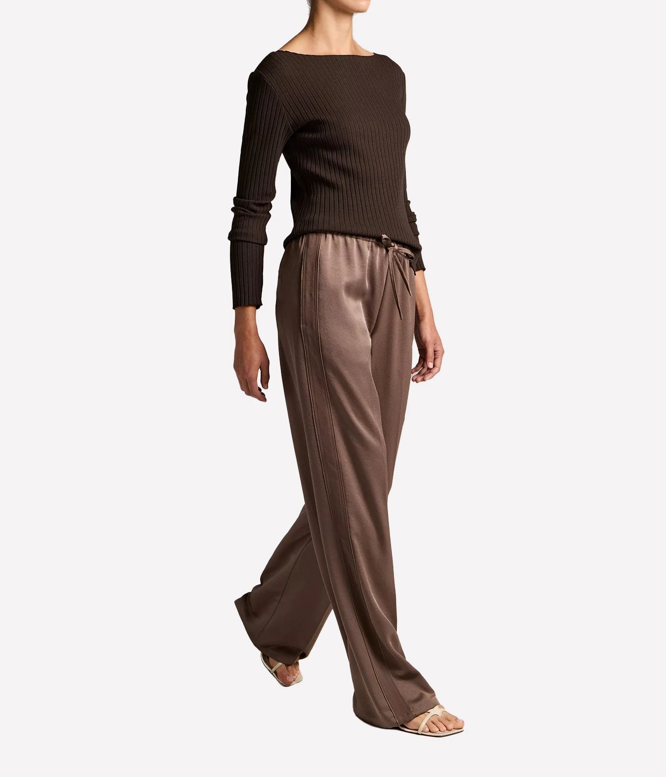 A model wearing a dark brown ribbed knit long-sleeve top and matching brown satin wide-leg pants