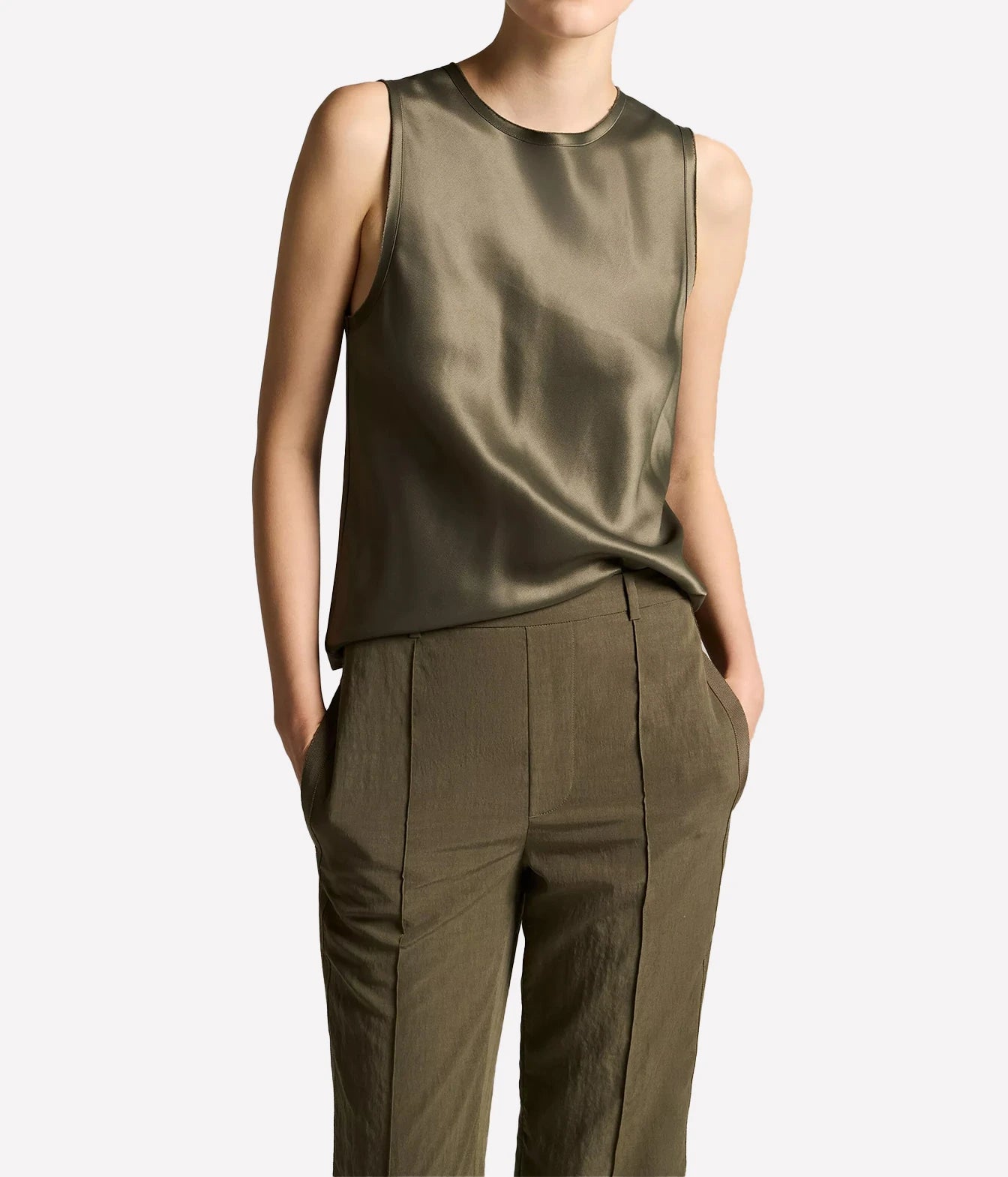 A model wearing a sleeveless olive green satin top and matching olive green trousers
