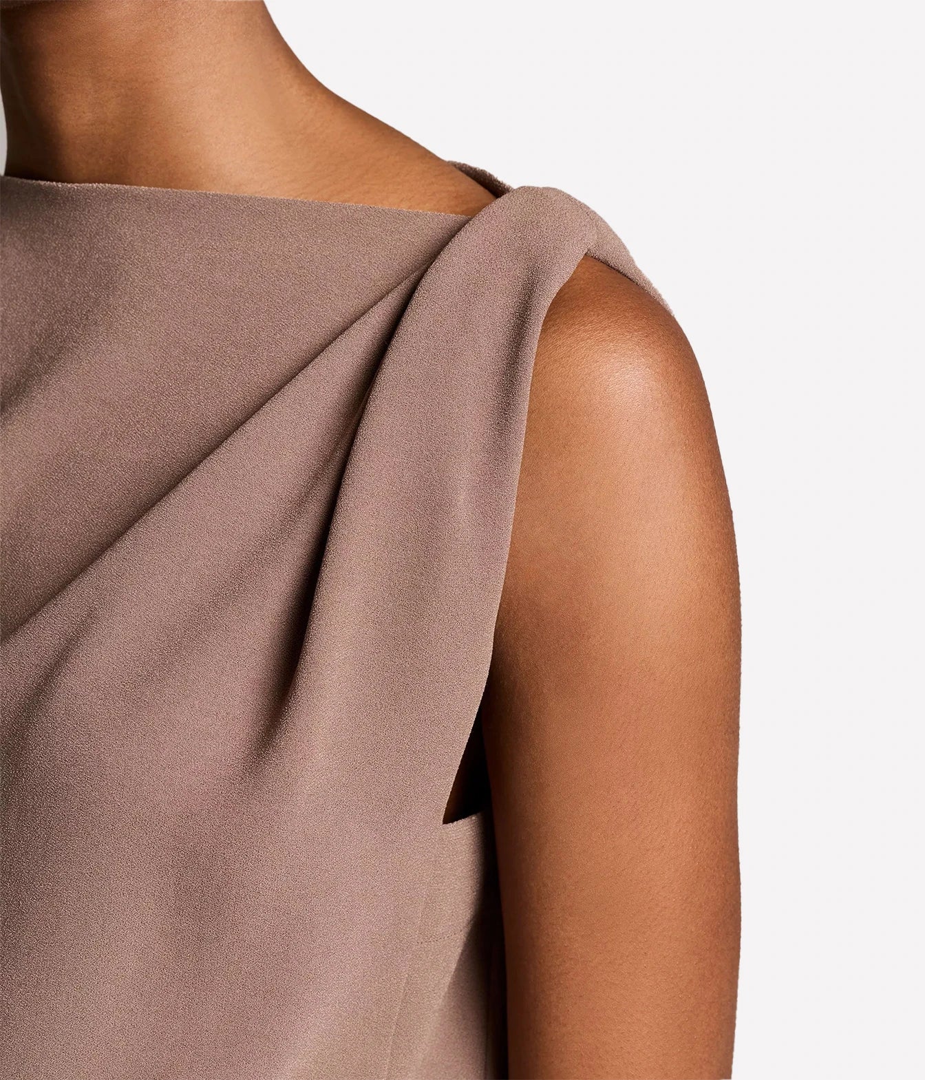 Close-up of a model wearing a draped, off-the-shoulder sleeveless top in a dusty taupe-brown color