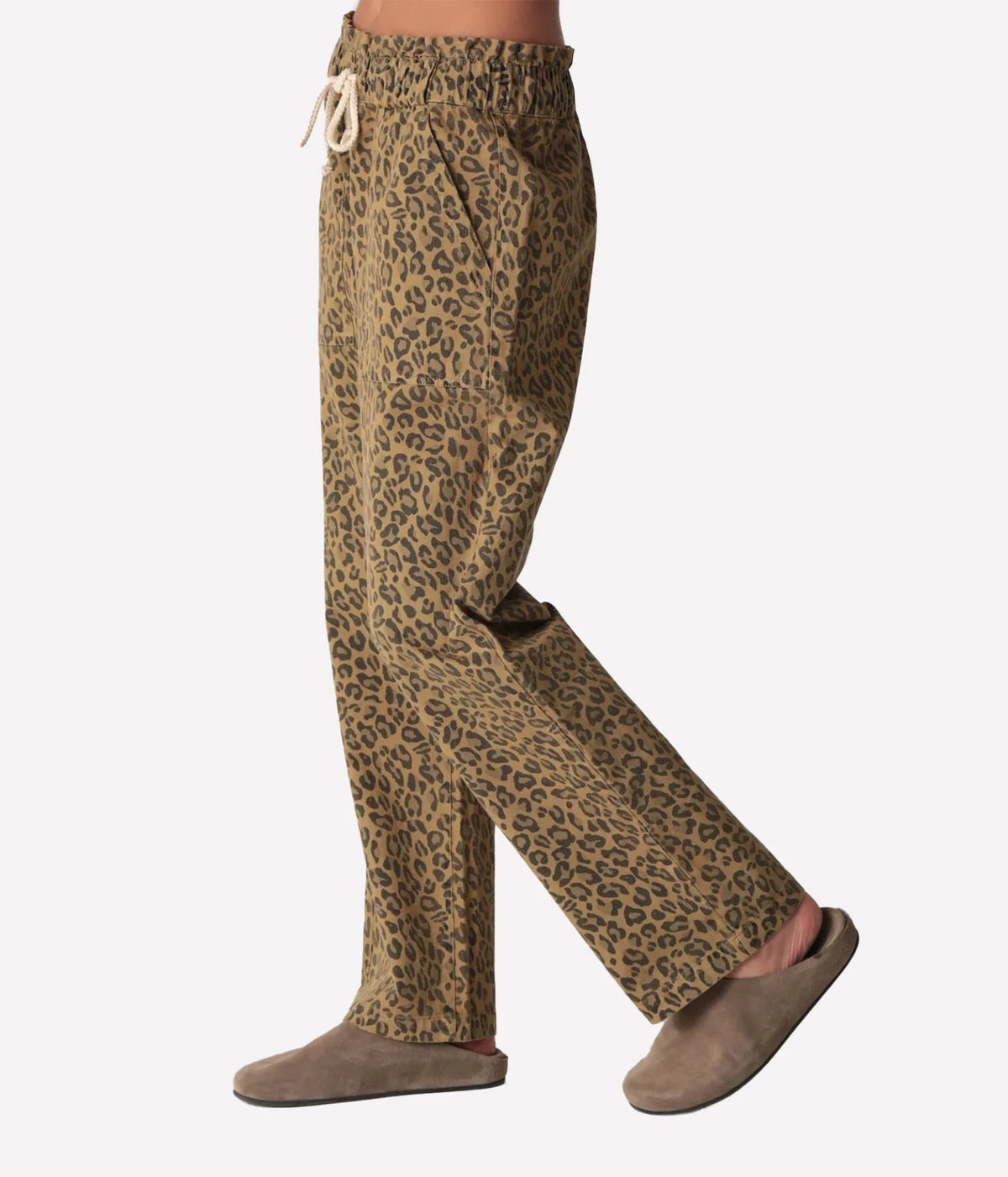 Side profile of a model mid-stride in the Electric Rose Easy Leopard Pant in Natural, showing the side pocket, gathered waistband and relaxed straight leg, with taupe suede clogs