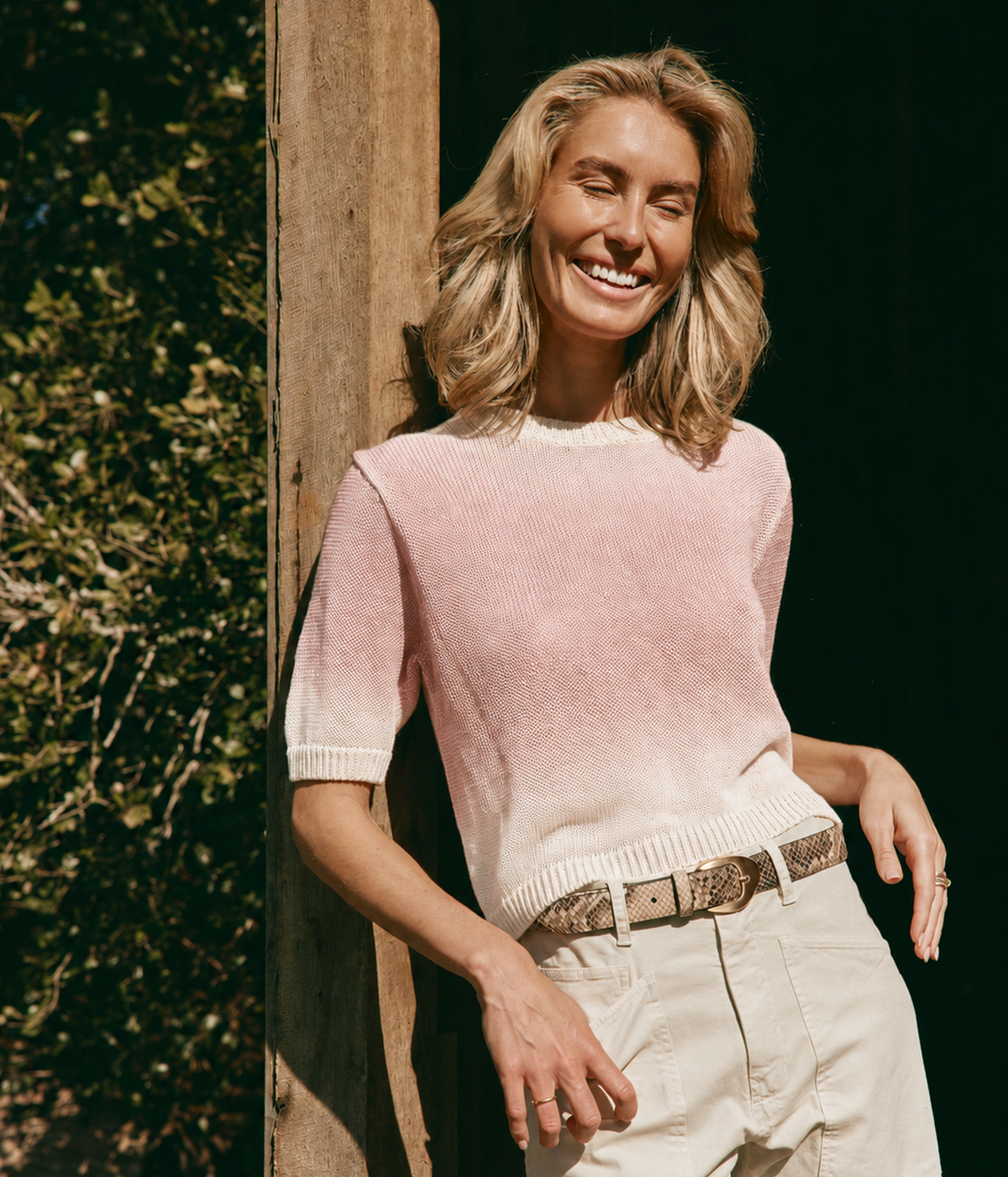 A short-sleeve knit sweater with a gradient color transition, fading from a dusty rose pink at the top to an off-white cream at the bottom, paired back with the Shon Pant in Stone with the Calexico Birkin Belt in Brown
