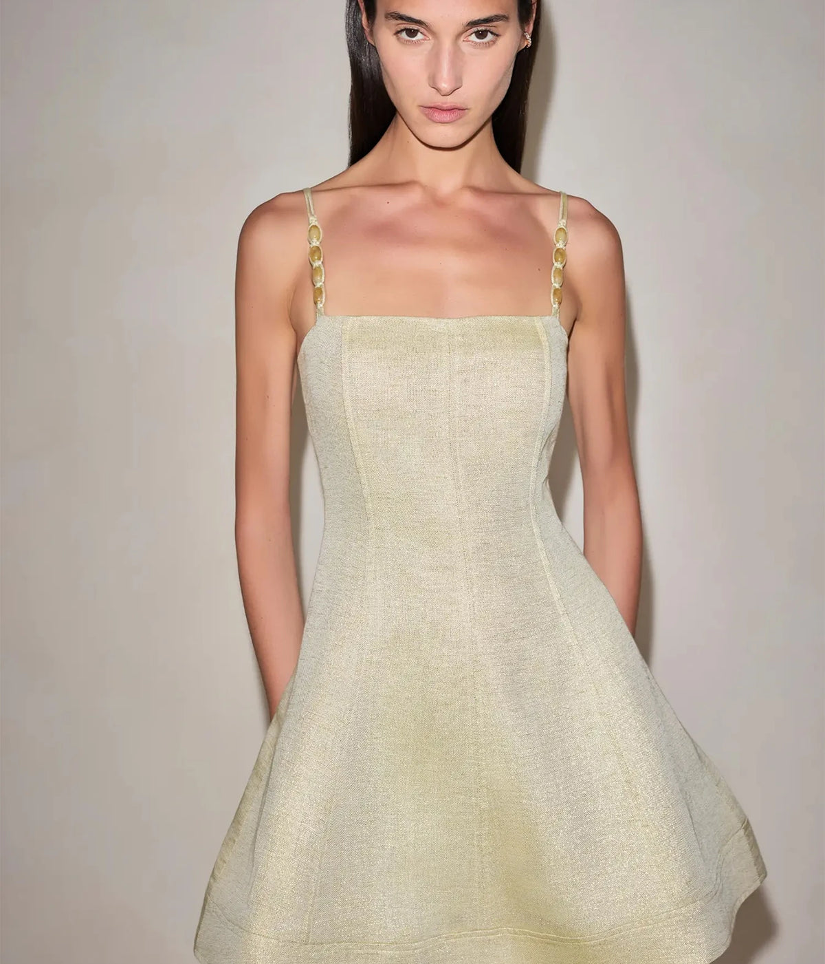 Close-up front view of a model wearing the Alexis Josefin Dress In Gold Mist, showing the square neckline, gold braided straps and sculpted bodice