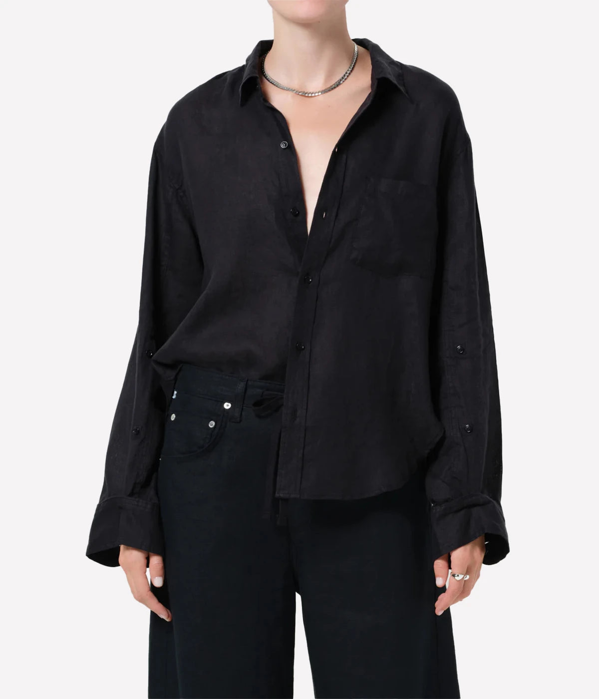 Person wearing a black button-up shirt and pants on a white background