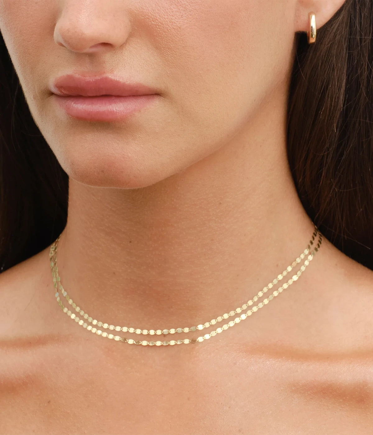 Model wearing the LANA Double Strand Petite Nude Necklace in Yellow Gold as a layered choker, with a small gold earring