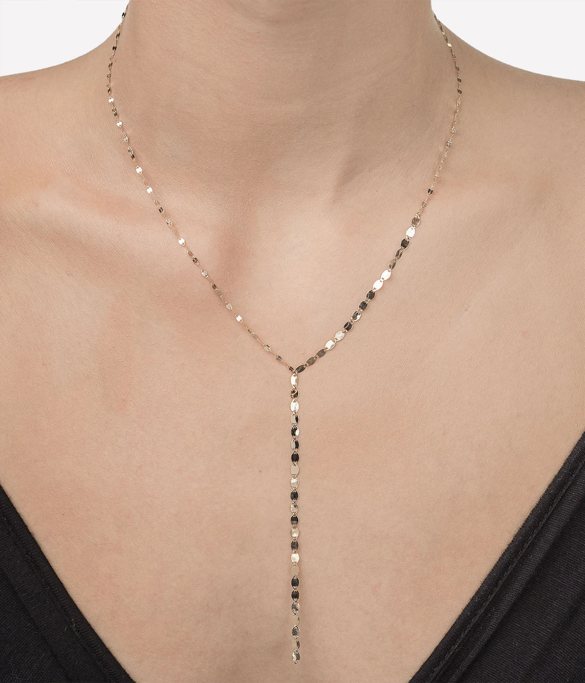 Close-up of a model wearing the LANA Nude Lariat Necklace in Yellow Gold with a black top, showing the long Y-shaped drop falling down the centre of the chest