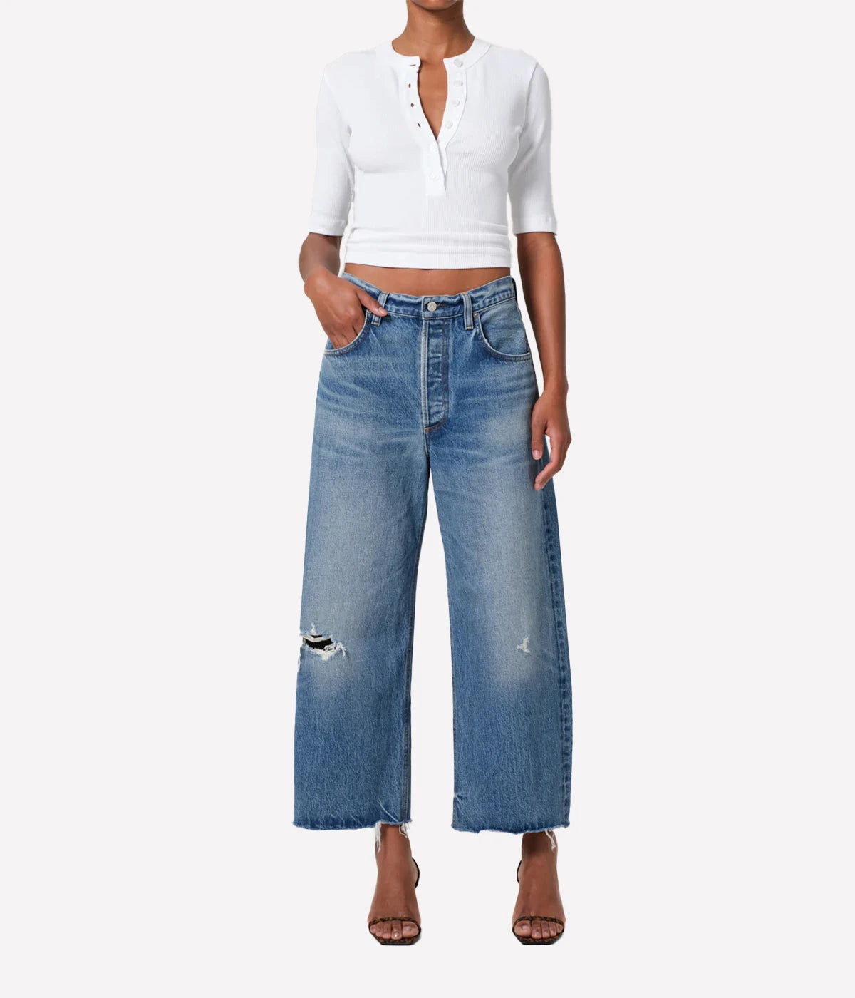 Person wearing a white cropped top and blue jeans on a white background