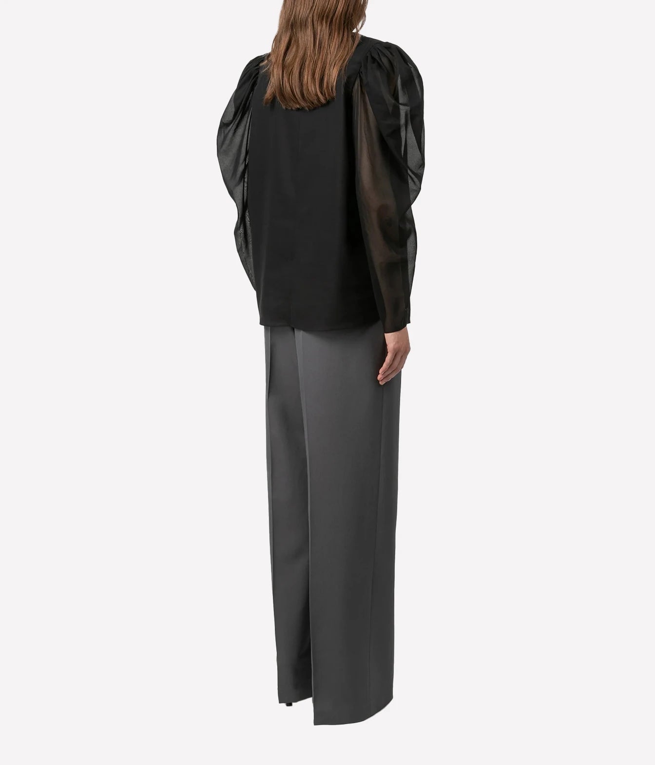 A model shown from the back wearing a black long-sleeve blouse with sheer puff sleeves and dark gray wide-leg trousers, set against a plain light gray background.