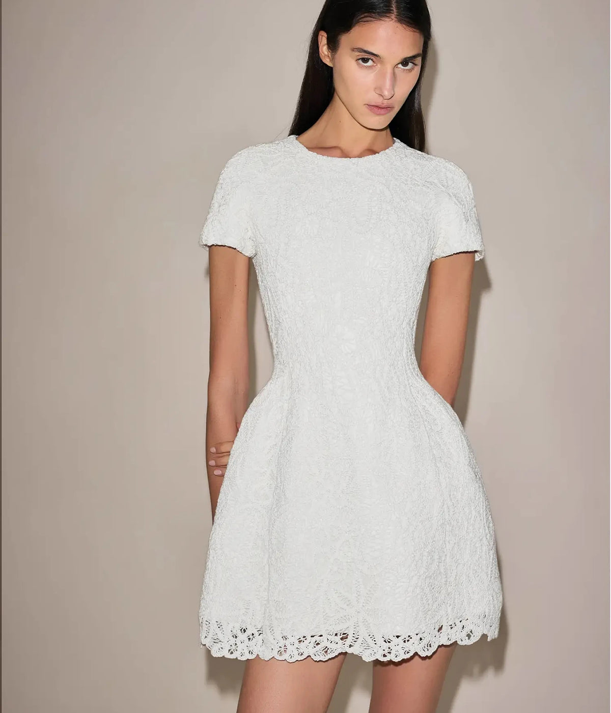 Three-quarter view of a model wearing the Alexis Regatta Dress In Floral Macrame turned slightly to the side, showing the shaped bodice and full skirt