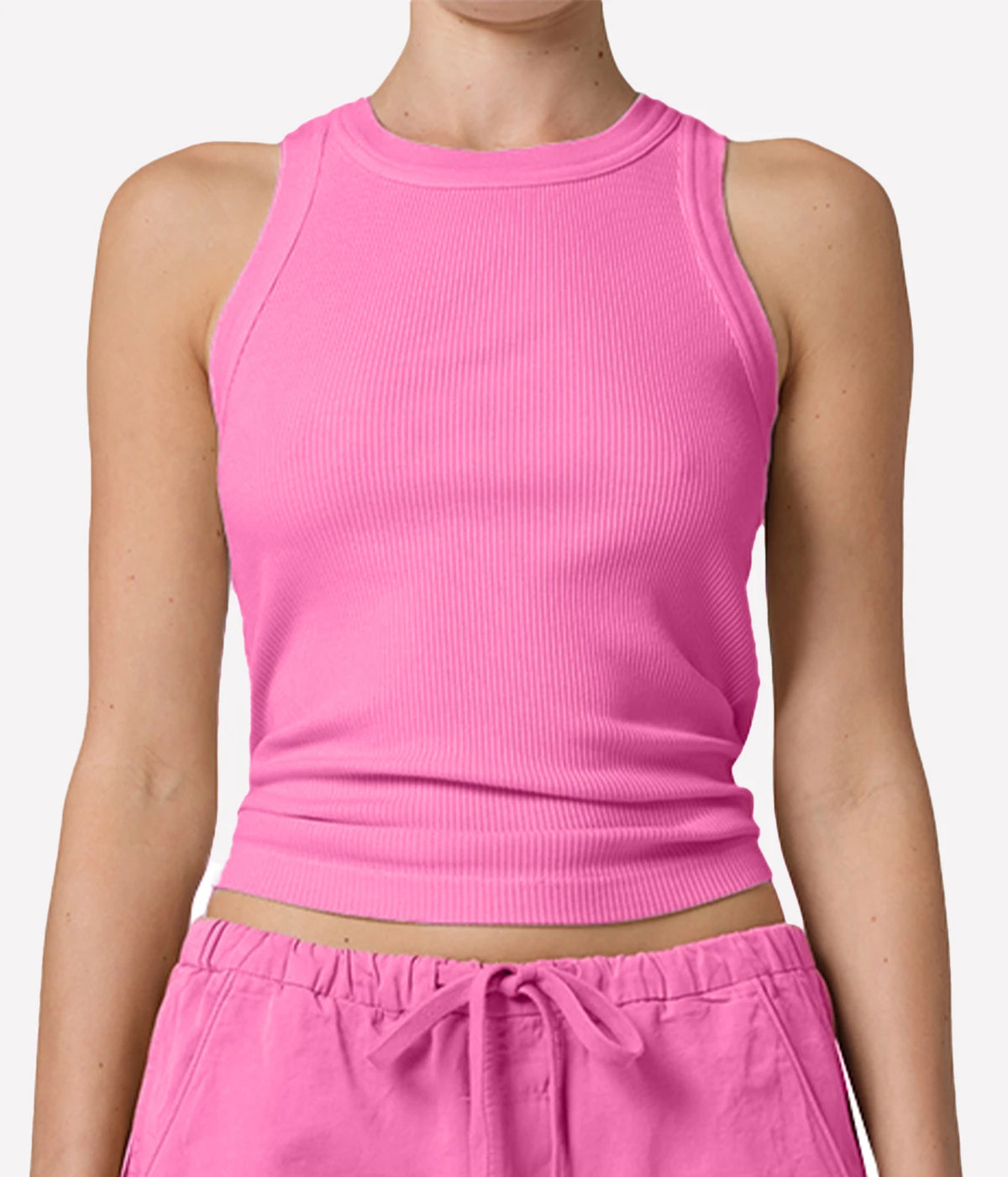 A close-up of a model wearing a bright pink ribbed sleeveless crop top - Isabel Rib Tank in raspberry