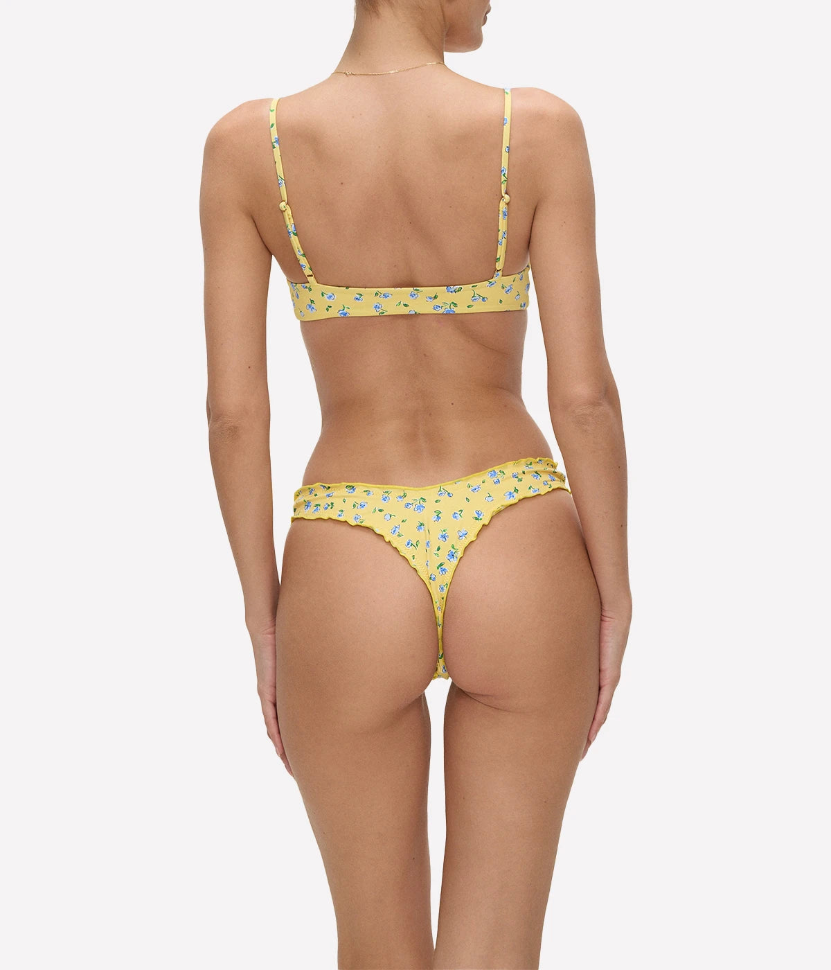 Yellow bikini bottoms with blue floral accents and frill detailing, styled for a playful and summery beach look.