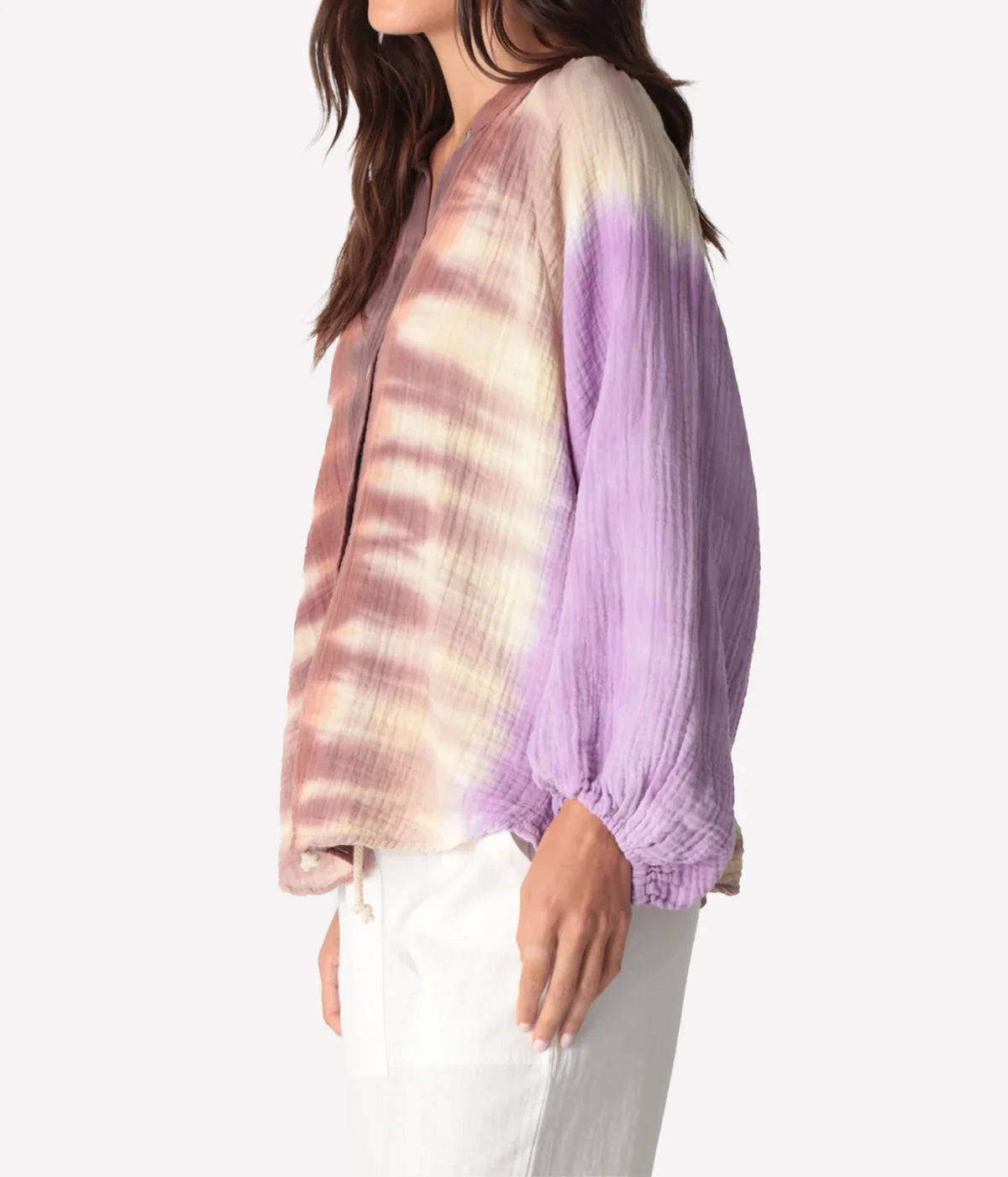 Side profile of a model wearing the Electric Rose Winnie Fade Shirt in Lavender Sepia, showing the lavender fade on the sleeve, gathered cuff and relaxed blouson fit, with white trousers