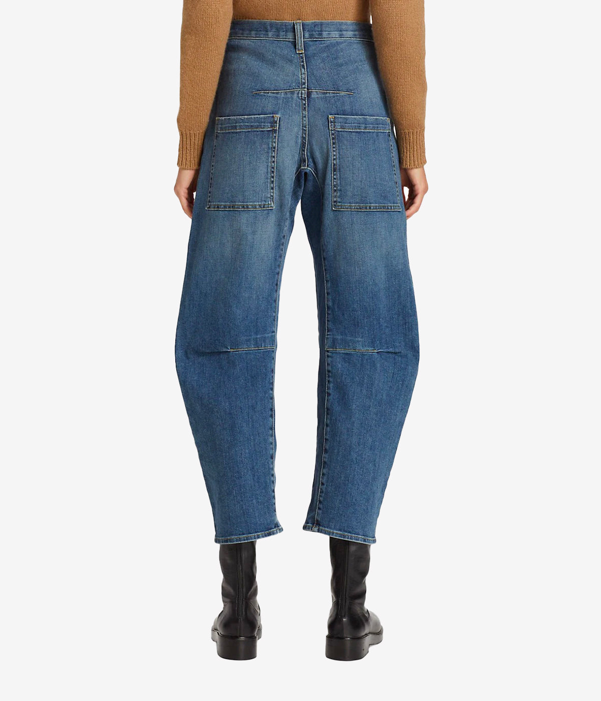 ALT text: High-rise barrel silhouette jeans in faded blue denim with distressed whiskering and uniquely placed pockets for a modern utilitarian style.