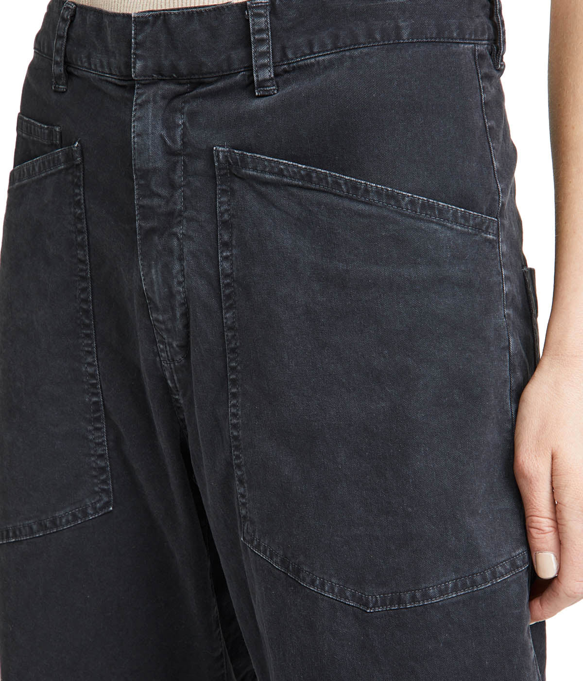 Oversized pants with curved silhouette and front patch pockets, styled with a T-shirt and sneakers for a casual chic look.