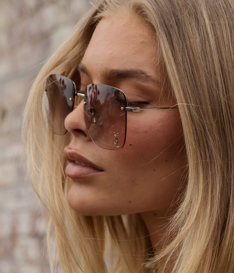 ALT text: Saint Laurent rimless sunglasses with gold frames, gradient-effect lenses, and Cassandre monogram