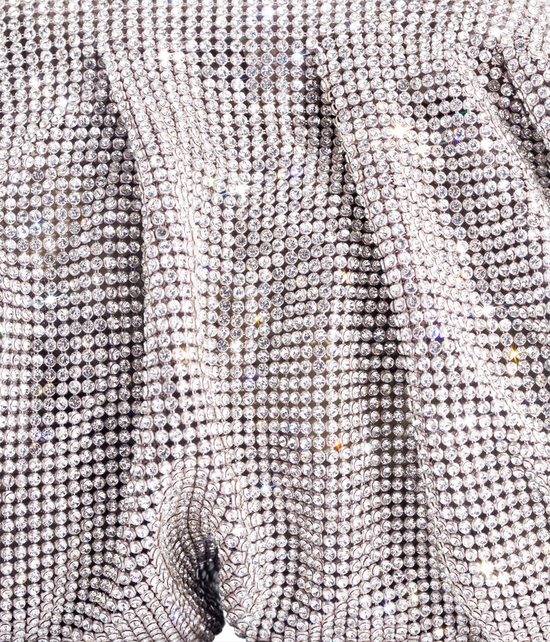 A close-up of a silver rhinestone-embellished fabric, showing the shimmering texture and draped folds of the material.