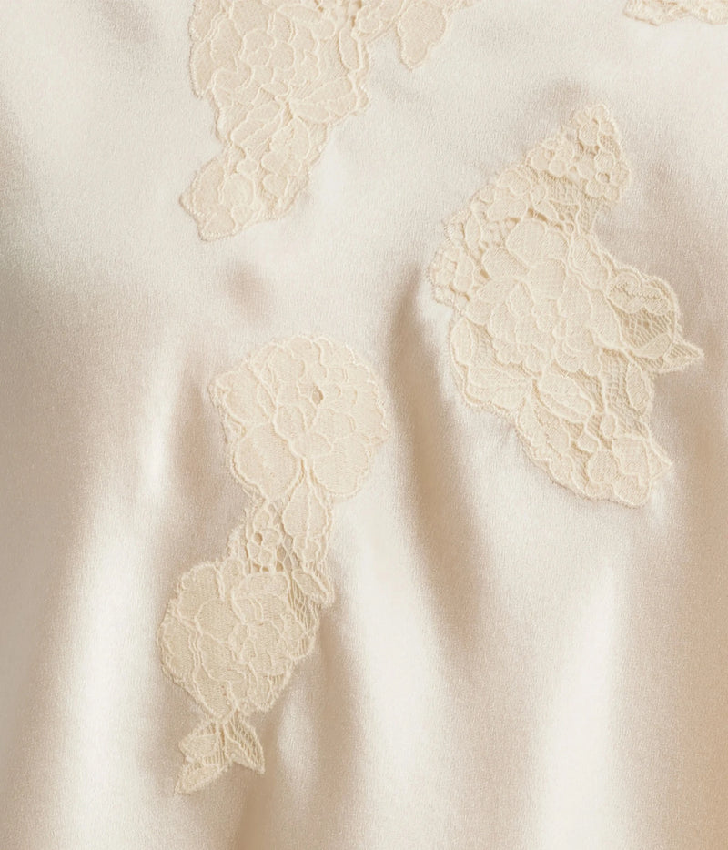 Close-up of a cream satin fabric with embroidered floral lace appliques.