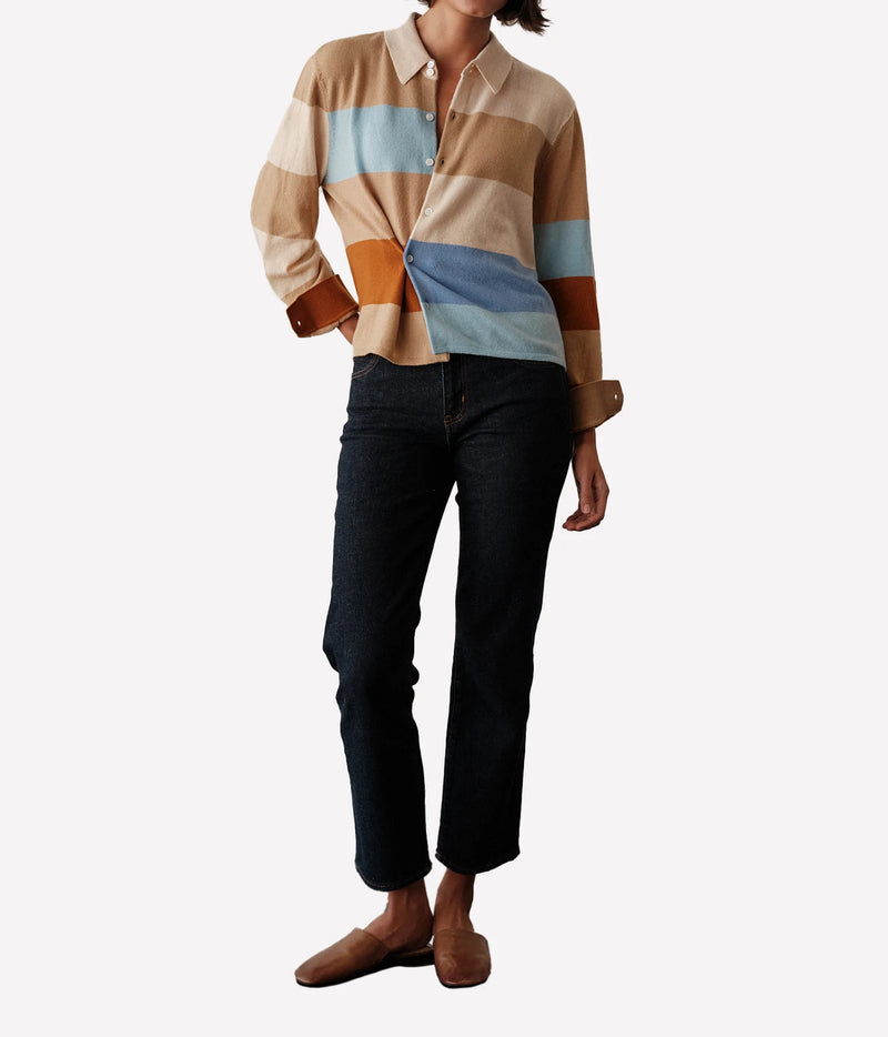 Front view of a model wearing the CISSA Rugby Cardigan in Desert Sky buttoned with black cropped straight-leg trousers and brown loafers, showing the camel, cream, blue and rust stripes