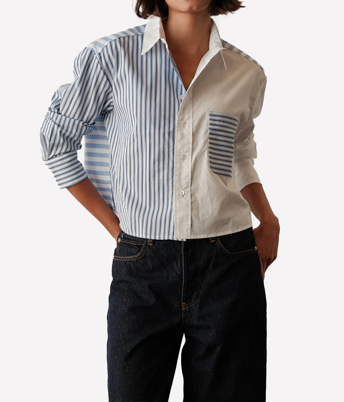 Front view of a model wearing the CISSA Shorty Shirt in Stripe Scrappy untucked over dark rinse jeans, showing the blue stripe and cream patchwork panels, white collar, striped chest pocket and rolled cuffs