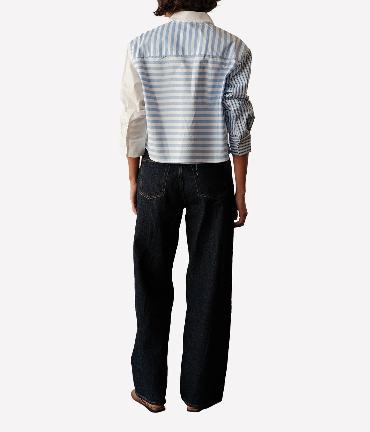 Back view of a model wearing the CISSA Shorty Shirt in Stripe Scrappy with dark wide-leg jeans, showing the striped back, contrast cream sleeve and cropped length