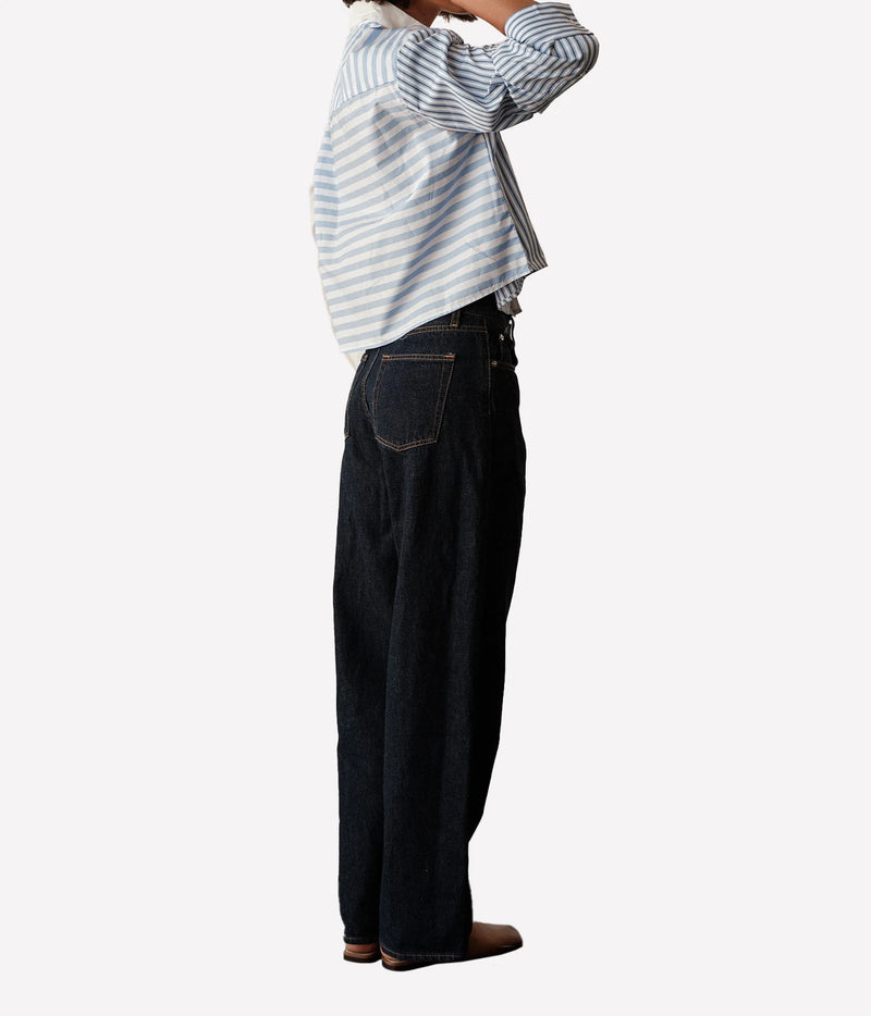 Side profile of a model wearing the CISSA Shorty Shirt in Stripe Scrappy with dark wide-leg jeans, one hand raised to her hair, showing the boxy cropped fit