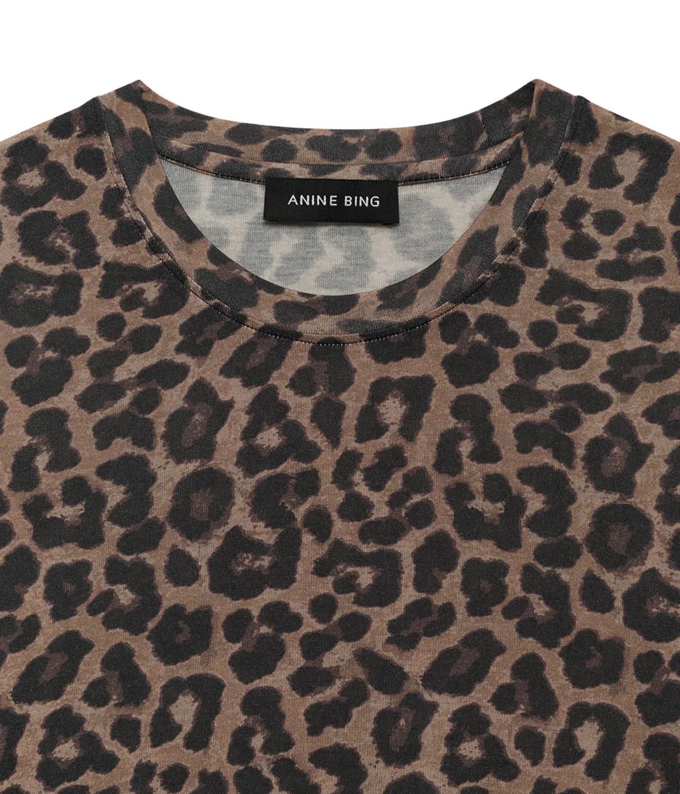 Close-up of a leopard print t-shirt by Anine Bing, featuring a brown and black animal pattern on a light beige base, with the brand label visible at the collar.