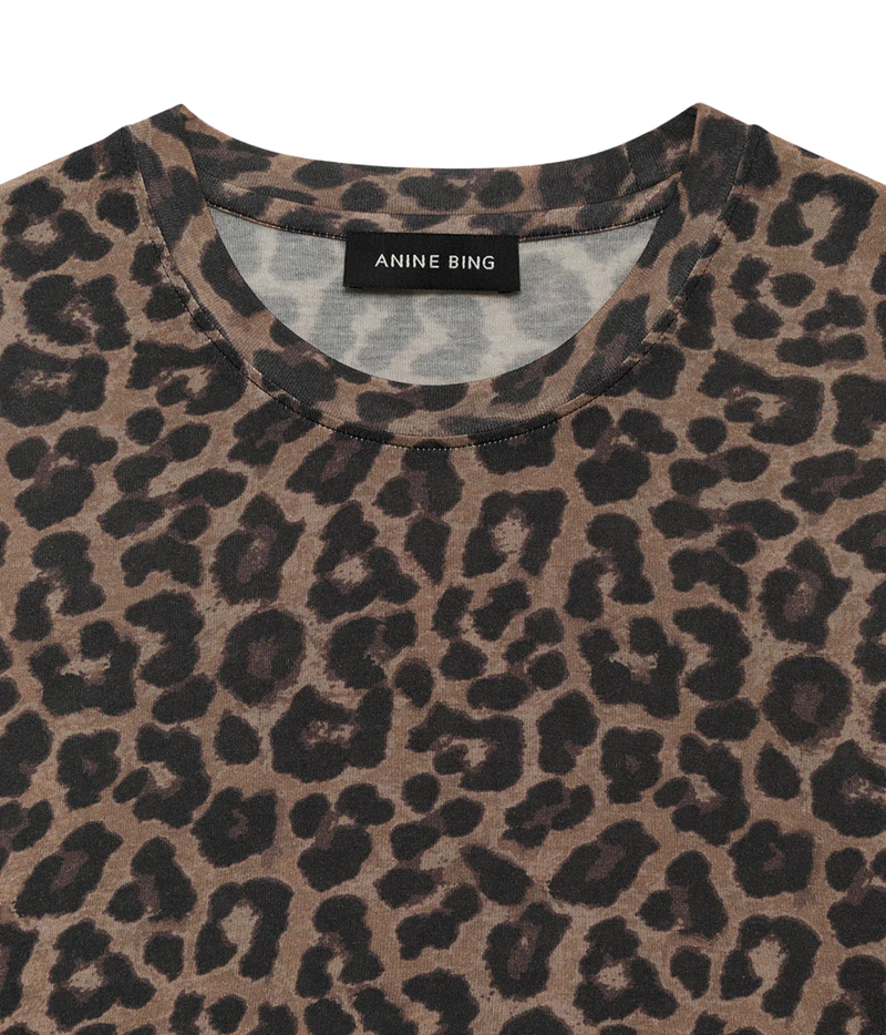 Close-up of a leopard print t-shirt by Anine Bing, featuring a brown and black animal pattern on a light beige base, with the brand label visible at the collar.