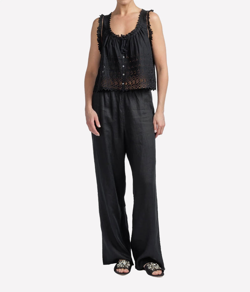 Person wearing a black eyelet blouse short sleeve and dark pants on a white background