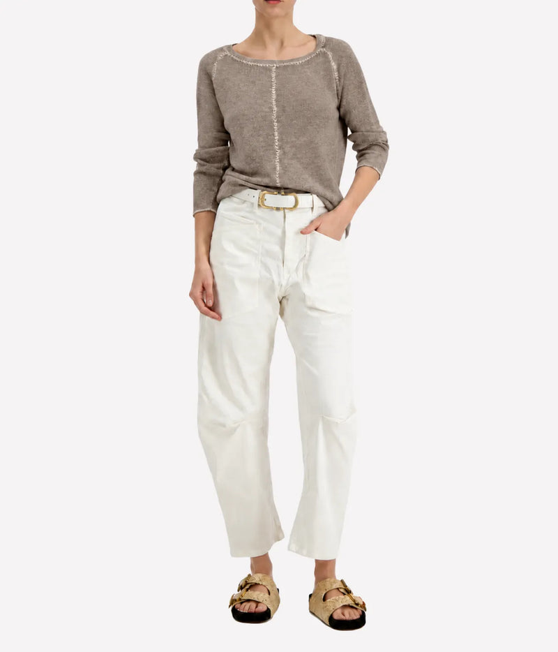 Model wearing the Avant Toi Maglia Pullover In Taupe tucked into cream barrel-leg trousers with a brown leather belt and dark sandals