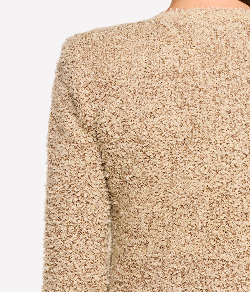 Close-up of a person wearing a beige fringed jacket