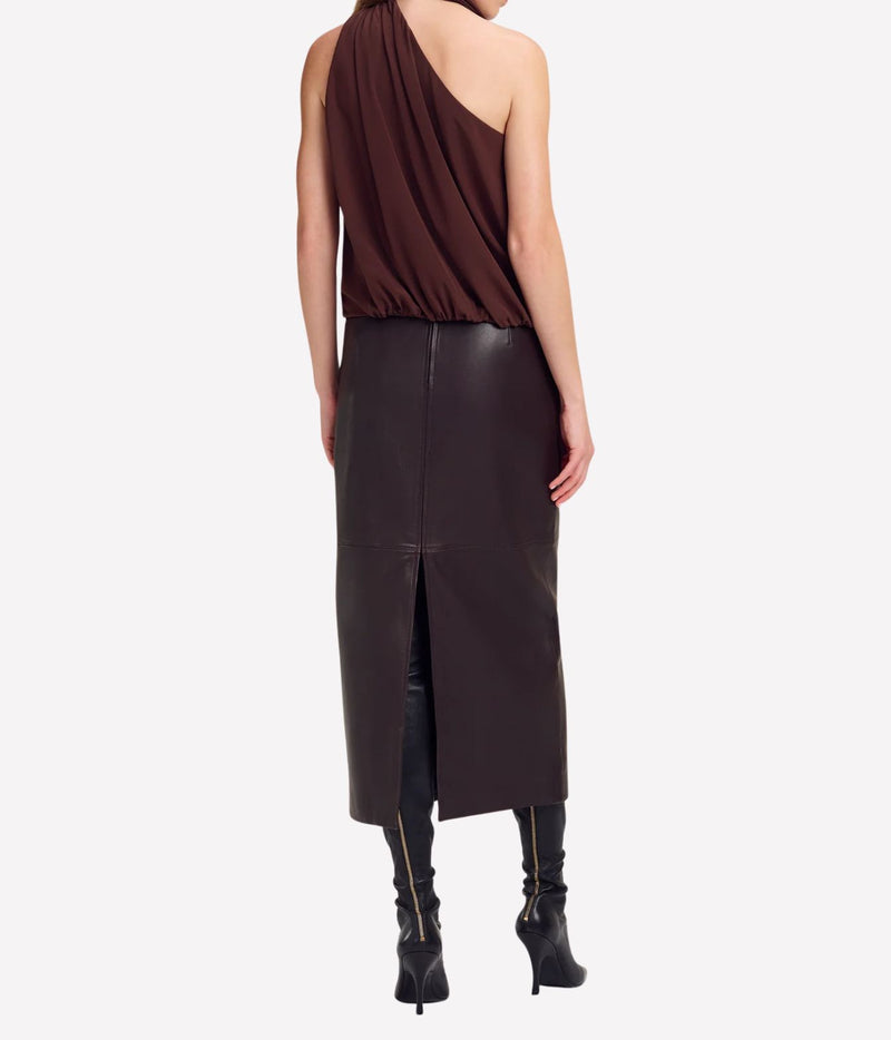 Back view of a model wearing the A.L.C. Celeste Top in Coffee, showing the bare shoulder and scarf collar, styled with a dark brown leather midi skirt with a back split and black heeled boots