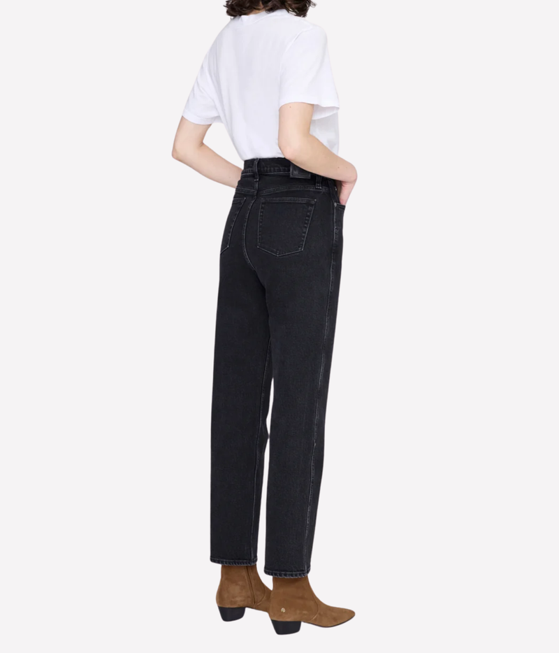 A model shown from the back wearing high-waisted black denim jeans, a white t-shirt, and brown ankle boots against a light gray background.