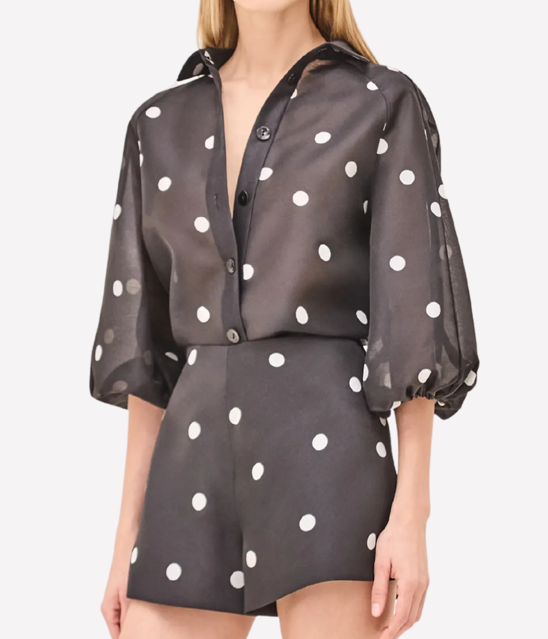 Woman wearing a black polka dot outfit on a white background