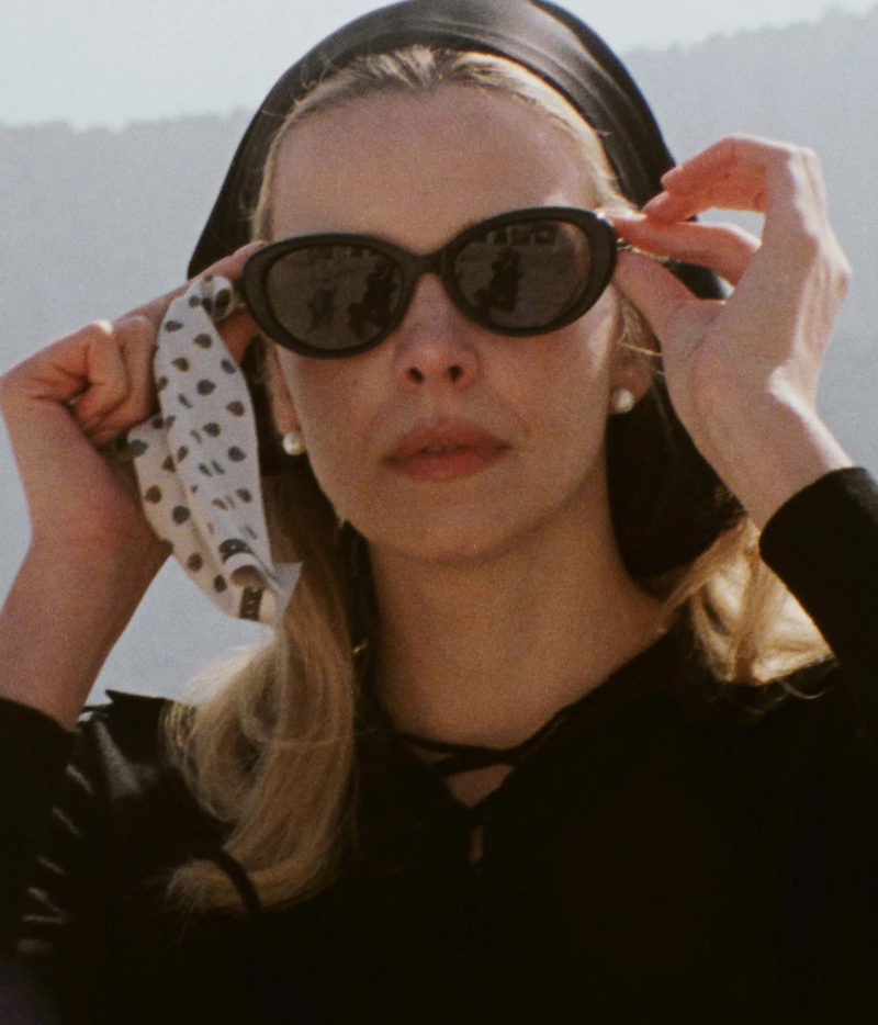 A woman outdoors wearing black cat-eye sunglasses