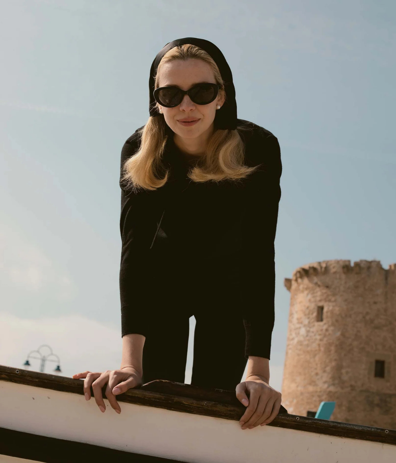 A woman wearing a black hooded long-sleeve top and black sunglasses