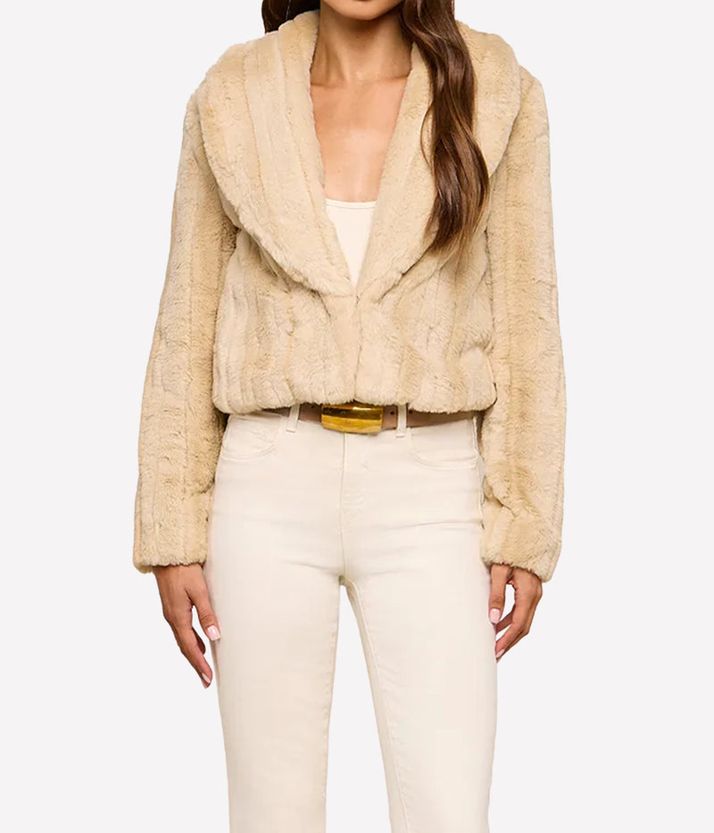 A woman wearing L'AGENCE Davy Faux Fur Jacket in Latte Striped Fur, styled with cream-coloured jeans and a brown belt with a gold buckle, against a plain white studio background.
