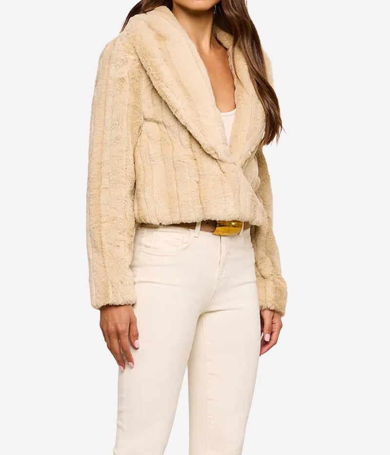 A woman wearing L'AGENCE Davy Faux Fur Jacket in Latte Striped Fur with a wide shawl collar, paired with cream-coloured jeans and a gold belt, against a plain white background.