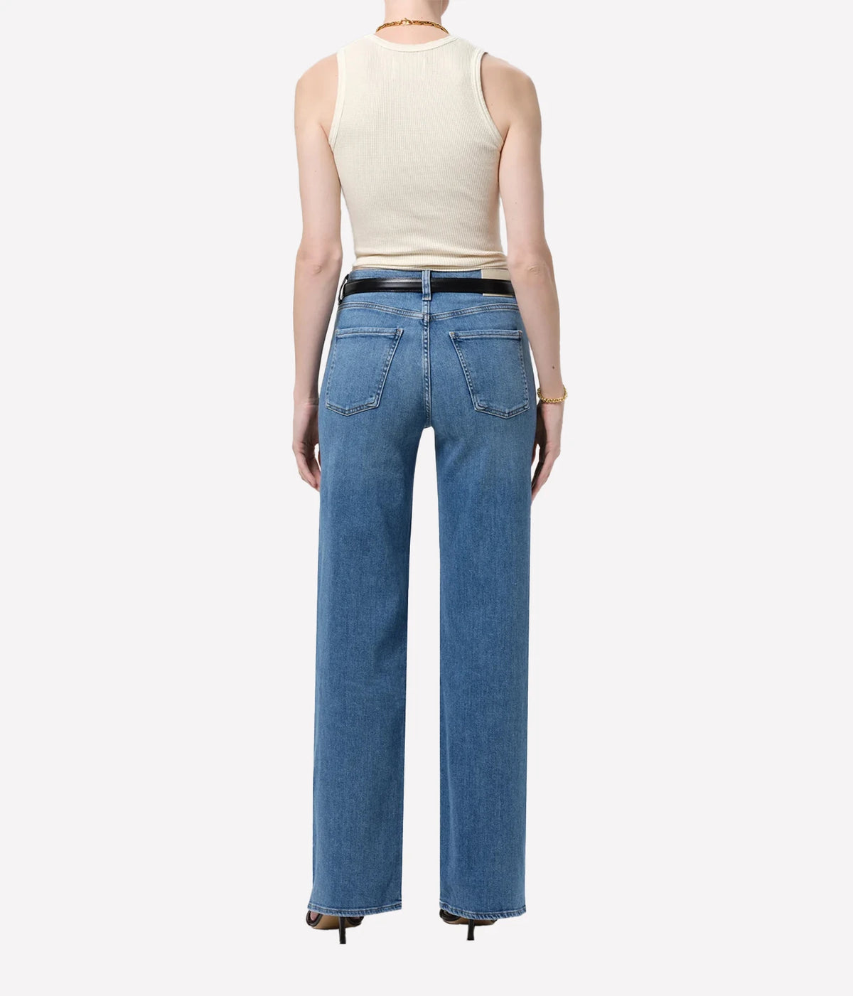 Full-length back view of a model wearing the Citizens Of Humanity Annina 33" Jean in Stella with a cream tank top tucked in and a black leather belt, showing the back pockets and long wide leg