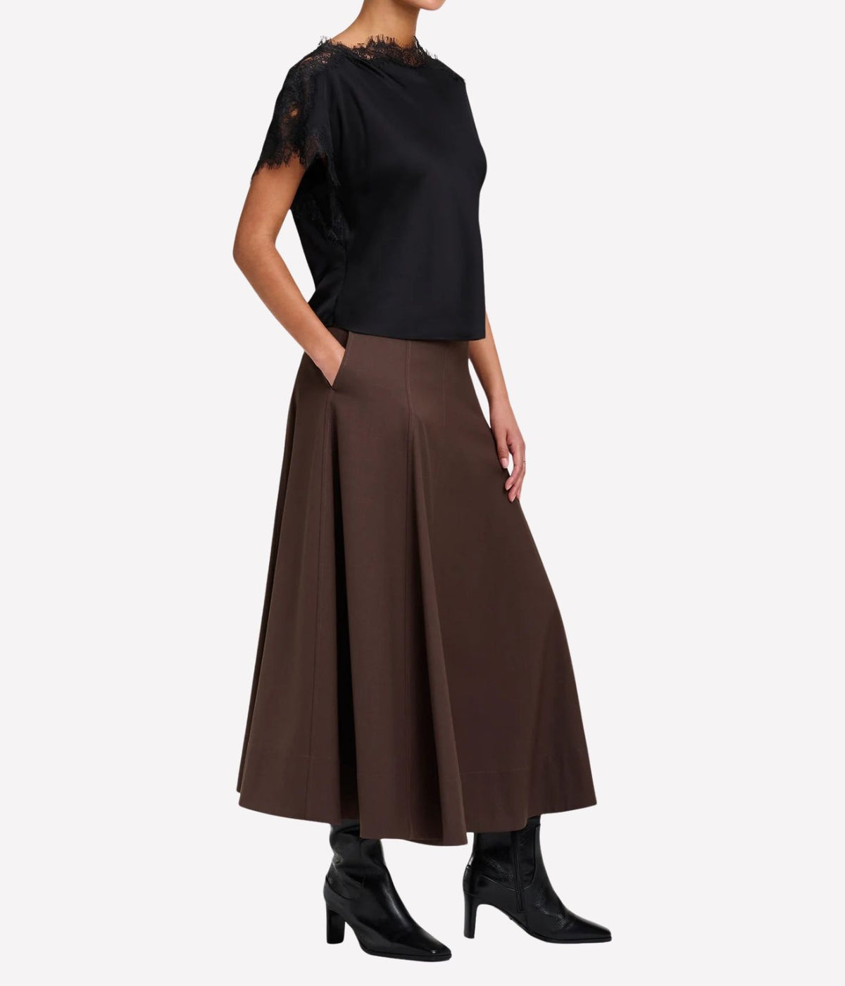 Full-length three-quarter view of a model wearing the A.L.C. Luna Top in Black tucked into a chocolate brown pleated midi skirt with black heeled ankle boots