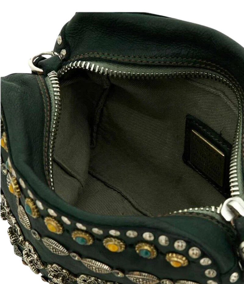 Close-up of the interior of a dark green leather handbag with silver-tone zippers, metal studs, and decorative embellishments. A small interior label is visible.