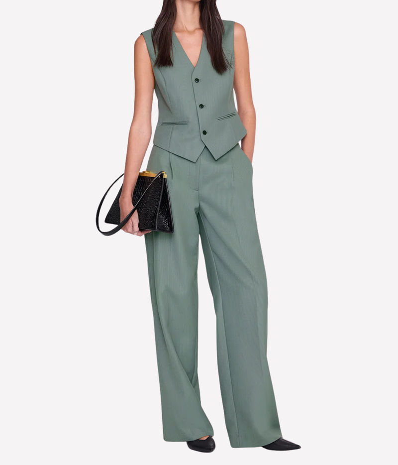 Model wearing the Anine Bing Mario Vest in Sage buttoned with matching sage wide-leg trousers, black pointed shoes and a black leather bag