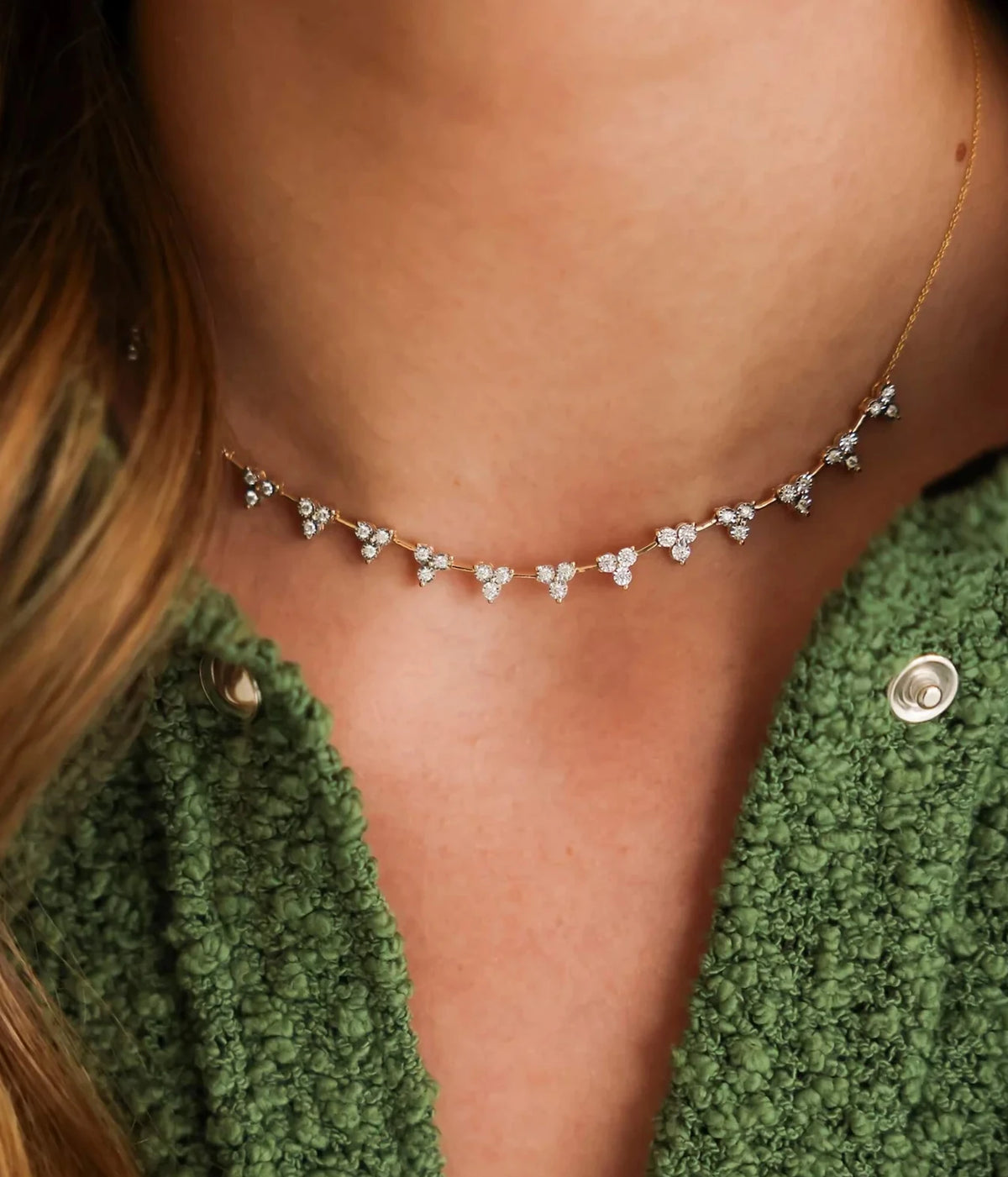 Close-up of a model wearing the Dana Rebecca Designs Ava Bea Interval Trio Tennis Necklace in 14k Yellow Gold at the collarbone with a green knit cardigan