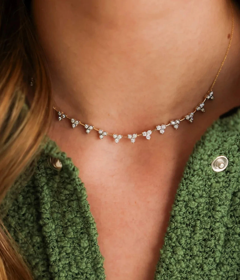 Close-up of a model wearing the Dana Rebecca Designs Ava Bea Interval Trio Tennis Necklace in 14k Yellow Gold at the collarbone with a green knit cardigan