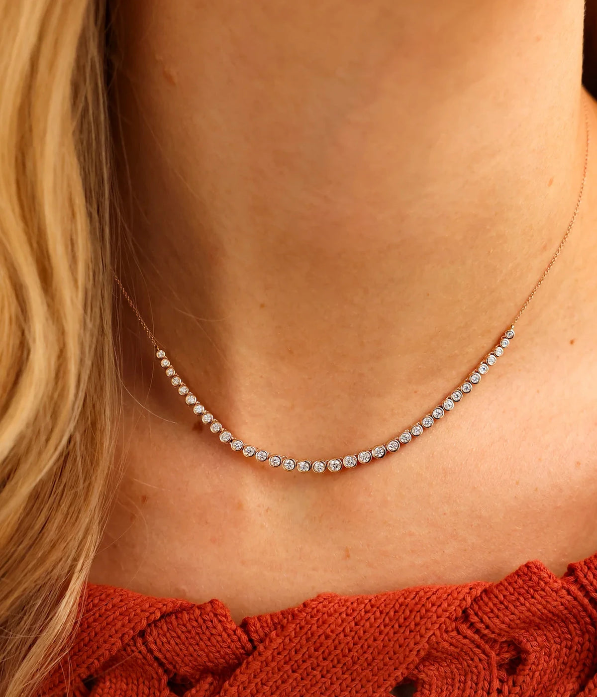 Model wearing the Dana Rebecca Designs Lulu Jack Graduating Bezel Tennis Necklace in 14k Yellow Gold at the collarbone with a rust-red textured top