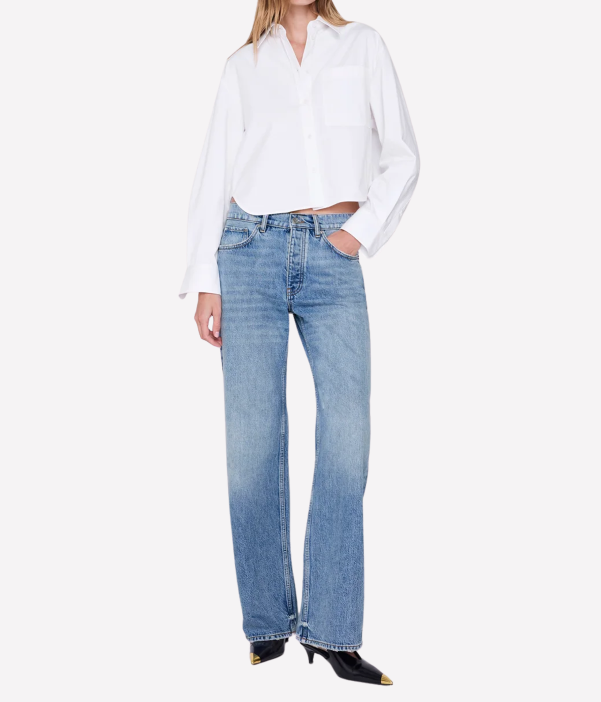 A model wearing light-wash blue straight-leg jeans, a white long-sleeve button-up shirt, and black pointed-toe heels, photographed against a clean white studio background.