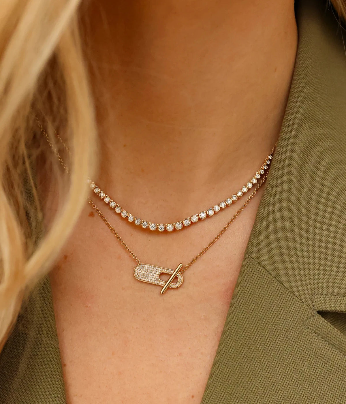 Model wearing the Dana Rebecca Designs Lulu Jack Graduating Bezel Tennis Necklace in 14k Yellow Gold layered with a gold chain and pavé link pendant, with an olive green top